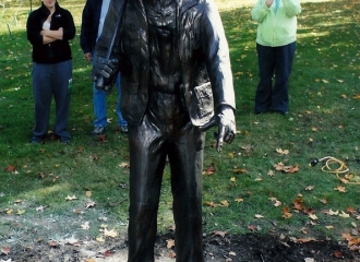 Bronze Coal Miner Statue in place, pointing towards the back of the stone which has fifty names on. All men lost their lives while working in a coal mine in Coshocton County, Ohio. First name dated back to 1877, last name on list from 1989. Debra (Bennett) Brown is standing to the right of the statue. October 18, 2013.
